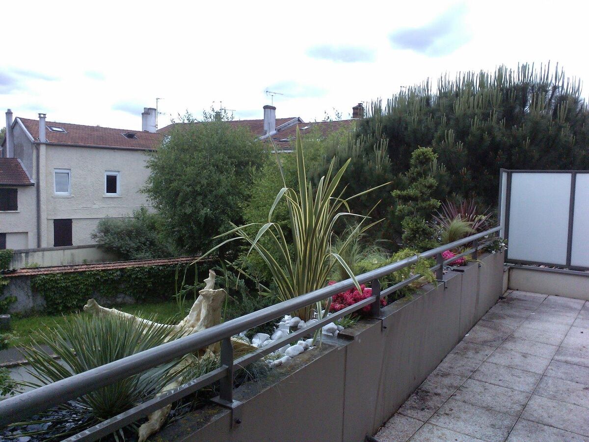 Balcon planté avec jardinières et graminées, avec vue sur un jardin